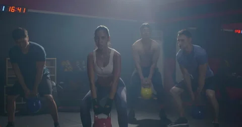 Muscular group in exercise gear standing in a row holding dumbbells during an Video stock 155370233