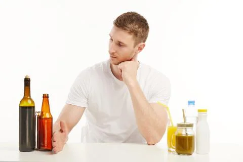 Muscular guy looking at different drinks in front of him. Stock Photos