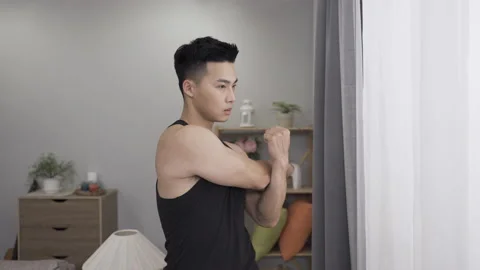 Muscular guy is warming up by stretching arms Stock Footage 201175232