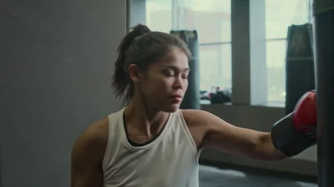 Muscular Hispanic Female Boxer Practicing on Punch Bag at Gym Stock Footage 277559698