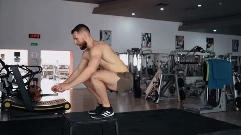 The muscular man, with a bare chest, performs jumps on an iron chair, training Stock Footage 156472033