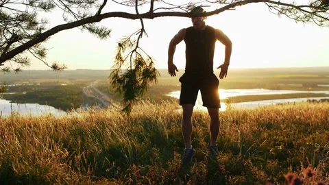 Muscular man boxer warming up his body on the field at early sunset Stock Footage 219952864