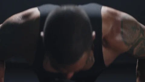 Muscular man does some push ups, and then takes a break on a dark background Stock Footage 77409503