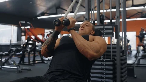 Muscular man doing cable rope triceps pull down exercise while working out Stock Footage 119045542