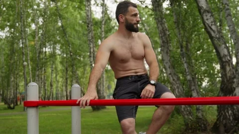 Muscular Man Doing Dips on Parallel Bars Outdoors Stock Footage 329599223