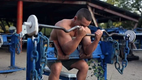 Muscular man doing exercises with barbell at the sports ground. Stock Footage 80119945