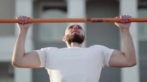 Muscular man doing pull-ups on horizontal bar. on workout area near house Stock Footage 143497817