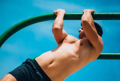 Muscular man doing pull-ups on horizontal bar 库存照片