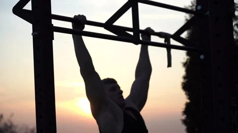 Muscular man doing pullups on sunset sky background. Concept of willpower Stock Footage 165770555