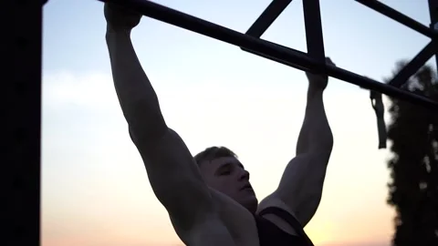 Muscular man doing pullups on sunset sky background. Calisthenics, healthy Stock Footage 165968703