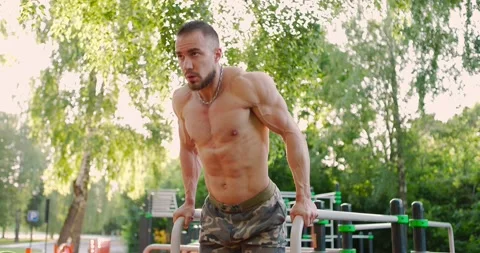Muscular man doing push ups on parallel bars at sports ground.Strong guy Stock Footage 157187877