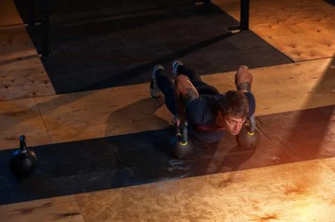 Muscular man doing push ups with kettle bell Stock Photos