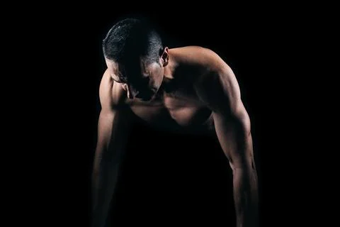 Muscular man doing push-ups with black background Stock Photos