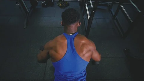 Muscular man doing reverse fly exercise on a bench in the gym with dumbbells Stock Footage 89504754