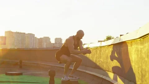 Muscular man doing squats training in the city at sunset. Stock Footage 247633226