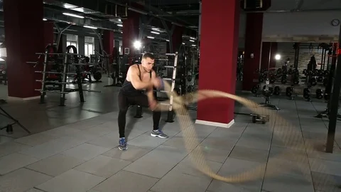 Muscular man doing waves with undulation ropes Stockbeeldmateriaal 73931656