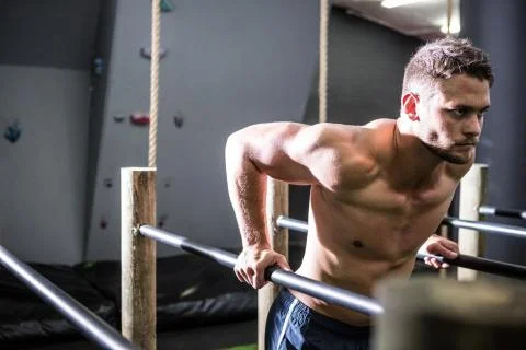 Muscular man exercising on parallel bars Stock Photos