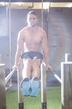Muscular man exercising on parallel bars Stock Photos