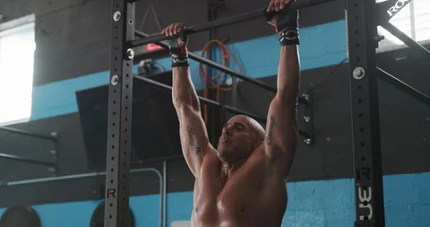Muscular man exercising on pull-up bar in gym Stock Footage 116389406