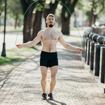 Muscular man jumping using skipping rope outdoors Stock Photos