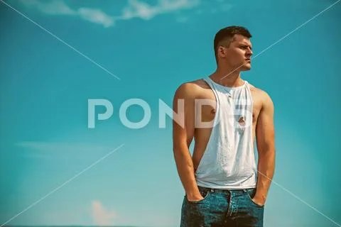 Muscular man with muscle torso sunny day on blue sky background, summer vacation Stock Photos