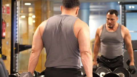 Muscular man performing dumbbell lateral raises in front of a mirror during.. Stock-Footage 344052787