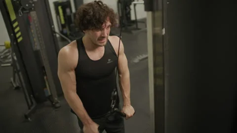 Muscular Man Performing Triceps Pushdowns on Cable Machine in Gym Stock Footage 302516949