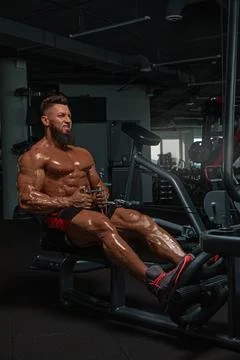 Muscular man performs workout on rowing machine in modern gym setting. focus is Stock Photos
