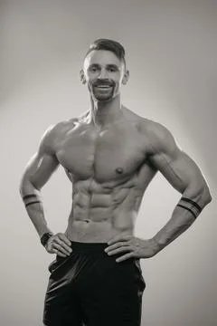 A muscular man is posing. The athletic guy is demonstrating his sporty physiq Stock Photos