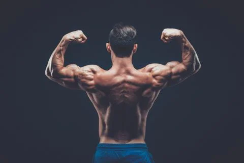 Muscular man posing in dark studio on black background Stock Photos
