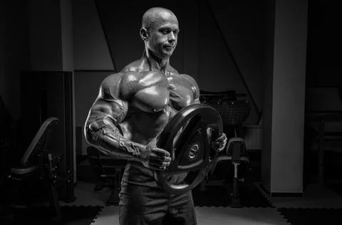 Muscular man posing in the gym with a barbell disc. Bodybuilding and powerl.. Foto stock
