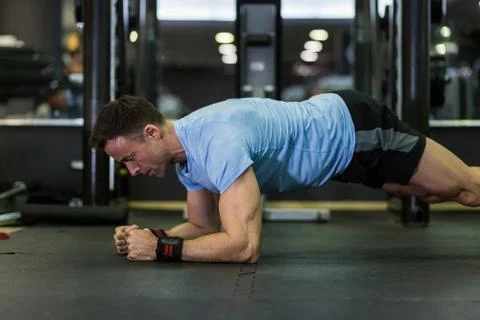 Muscular man practicing elbow plank exercise at the gym. Stock Photos