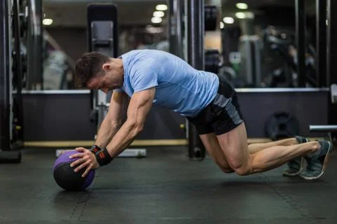 Muscular man practicing plank exercise using a ball at the gym. Stock Photos