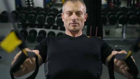 Muscular man pulls himself up on TRX belts 4K Slow Mo Stock-Footage 100257887