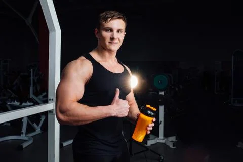 Muscular Man Resting After Exercise And Drinking From Shaker While Showing Stock Photos