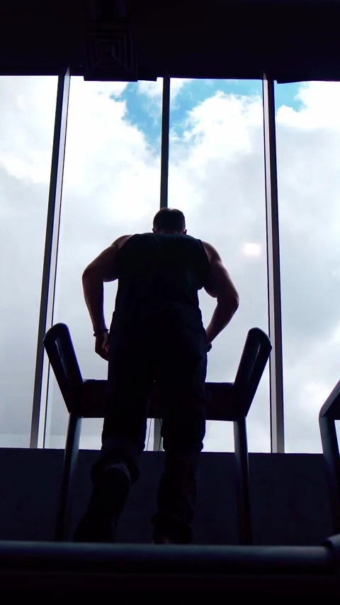 Muscular man running on treadmill with view of sky through window. Stock Footage 337468616