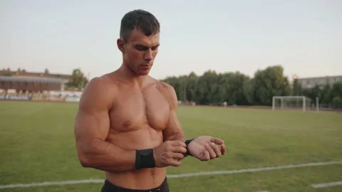 A muscular man takes a break between strength exercises in the stadium and Stock Footage 157184327