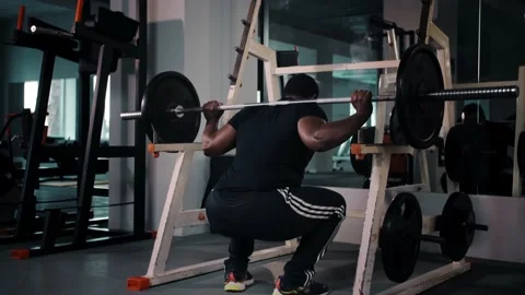 Muscular man training with barbell, doing back squats in gym, back view. Black Stock Footage 225716141