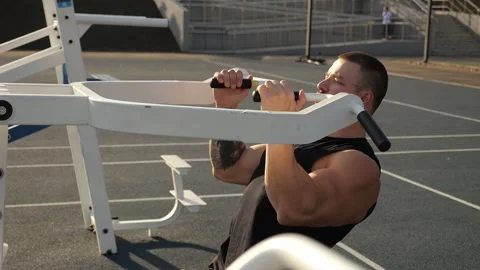 A muscular man trains on outdoor simulators,does exercises for his back and arms Stock Footage 287582668