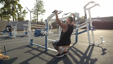 A muscular man trains on outdoor simulators,does exercises for his back and arms Stock Footage 295842581