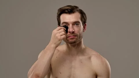 Muscular Man Using Gua Sha Tool for Facial Massage Therapy Stock Footage 310492081