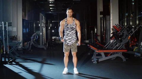 Muscular man workout lifts hands with dumbbells gym and smiling Stock Footage