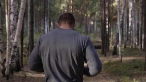 Muscular runner running on road through forest. Back view. Athletic man running Stock Footage