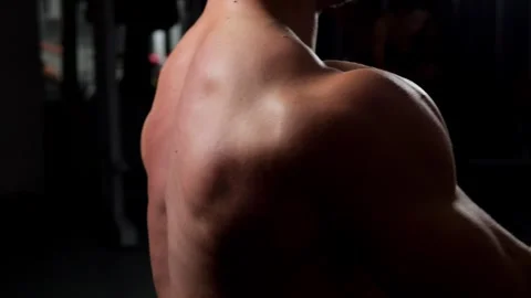 A muscular shirtless man performs exercises on a back simulator in the gym. Stock Footage 295843039