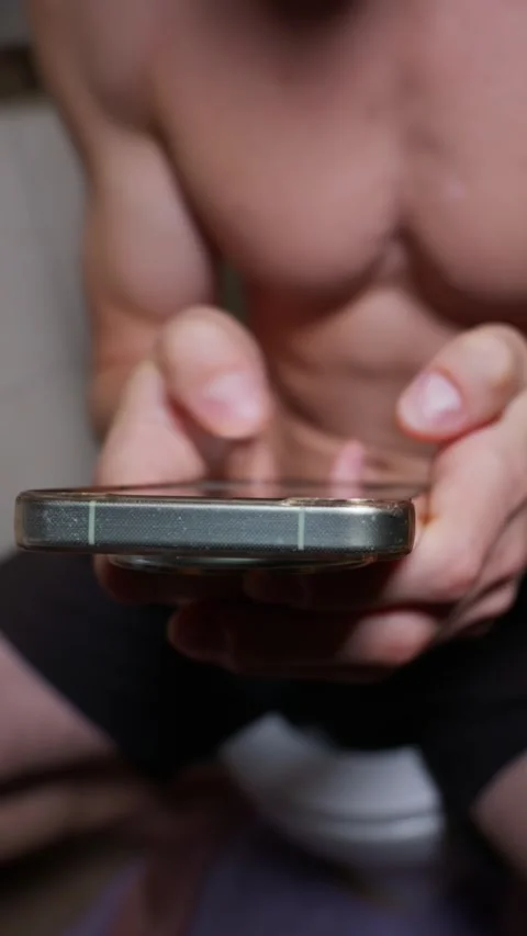 Muscular Shirtless Man Using Smartphone While Sitting on Toilet in Bathroom Stock Footage 339210620