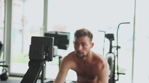 A muscular sport man check the program and working out on rowing machine in gym Stock Footage 250178376