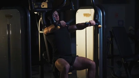 Muscular strong man doing pec deck butterflies and looking forward while exercis Stock Footage 127713992