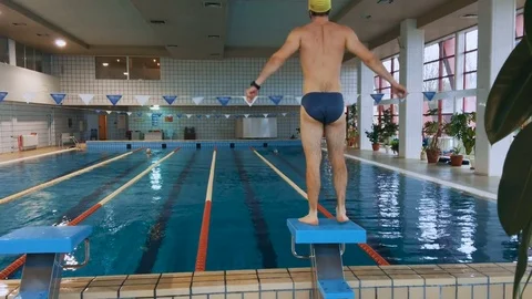 Muscular swimmer warming up and jumping into the pool and swim a distance. 4K. Stock Footage 72964106