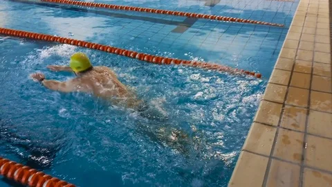 Muscular swimmer warming up and jumping into the pool and swim a distance. 4K. Stock Footage 72966375