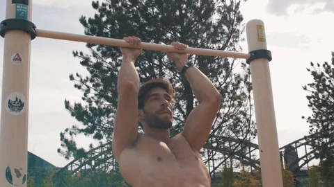 Muscular white man doing pull ups at a calisthenics bar in sun getting exhausted Stock Footage 87261674